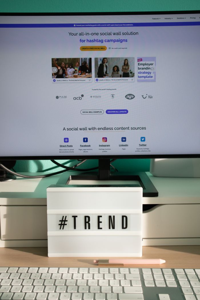 Services A clean and modern desk setup with a lightbox displaying '#TREND' and a computer monitor showing a social wall solution.