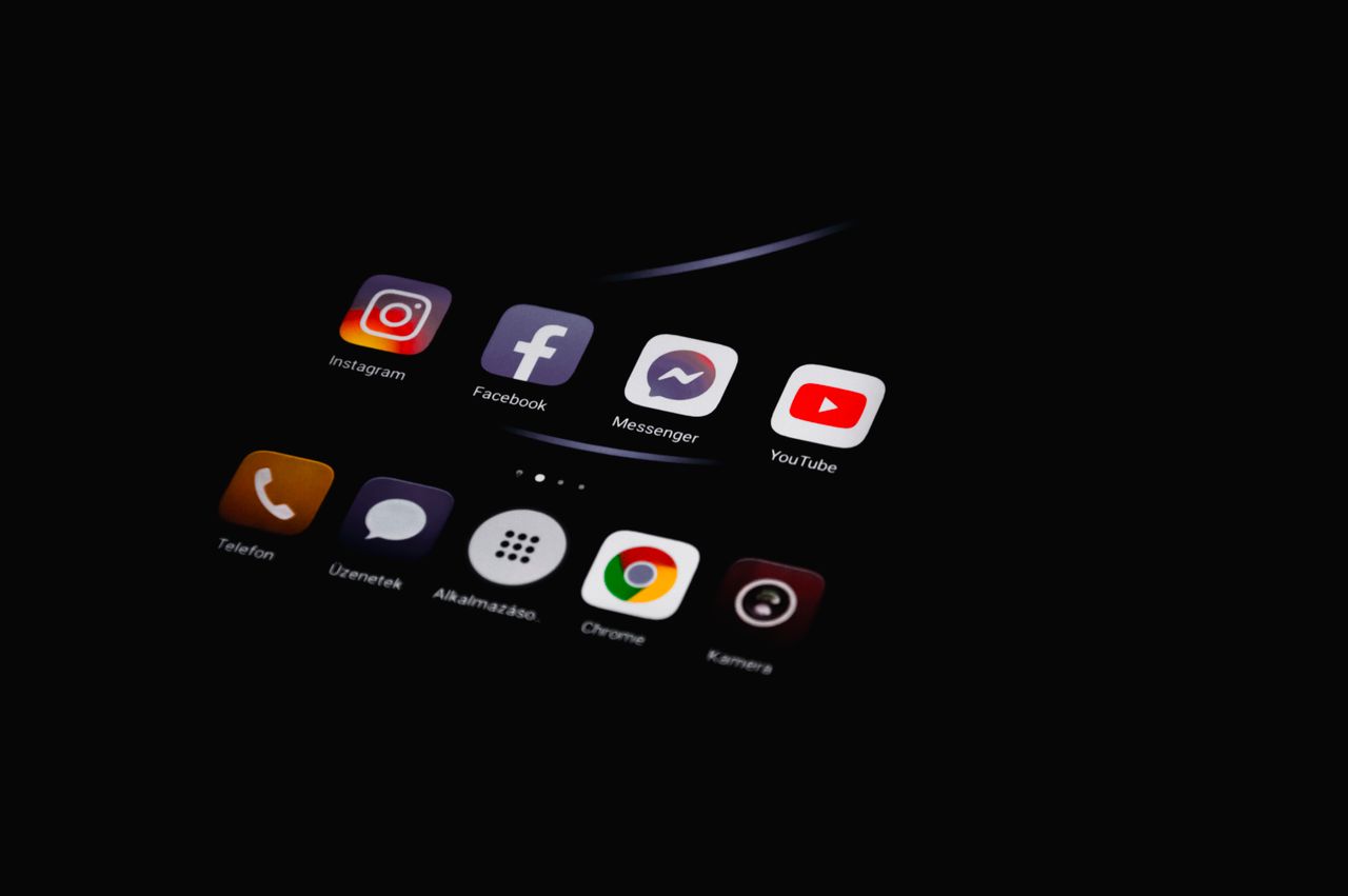 About Close-up of smartphone displaying popular social media apps in dim lighting.