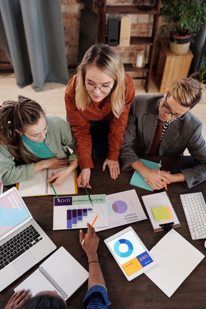 Services Top view of a diverse group discussing business reports and charts around a desk.