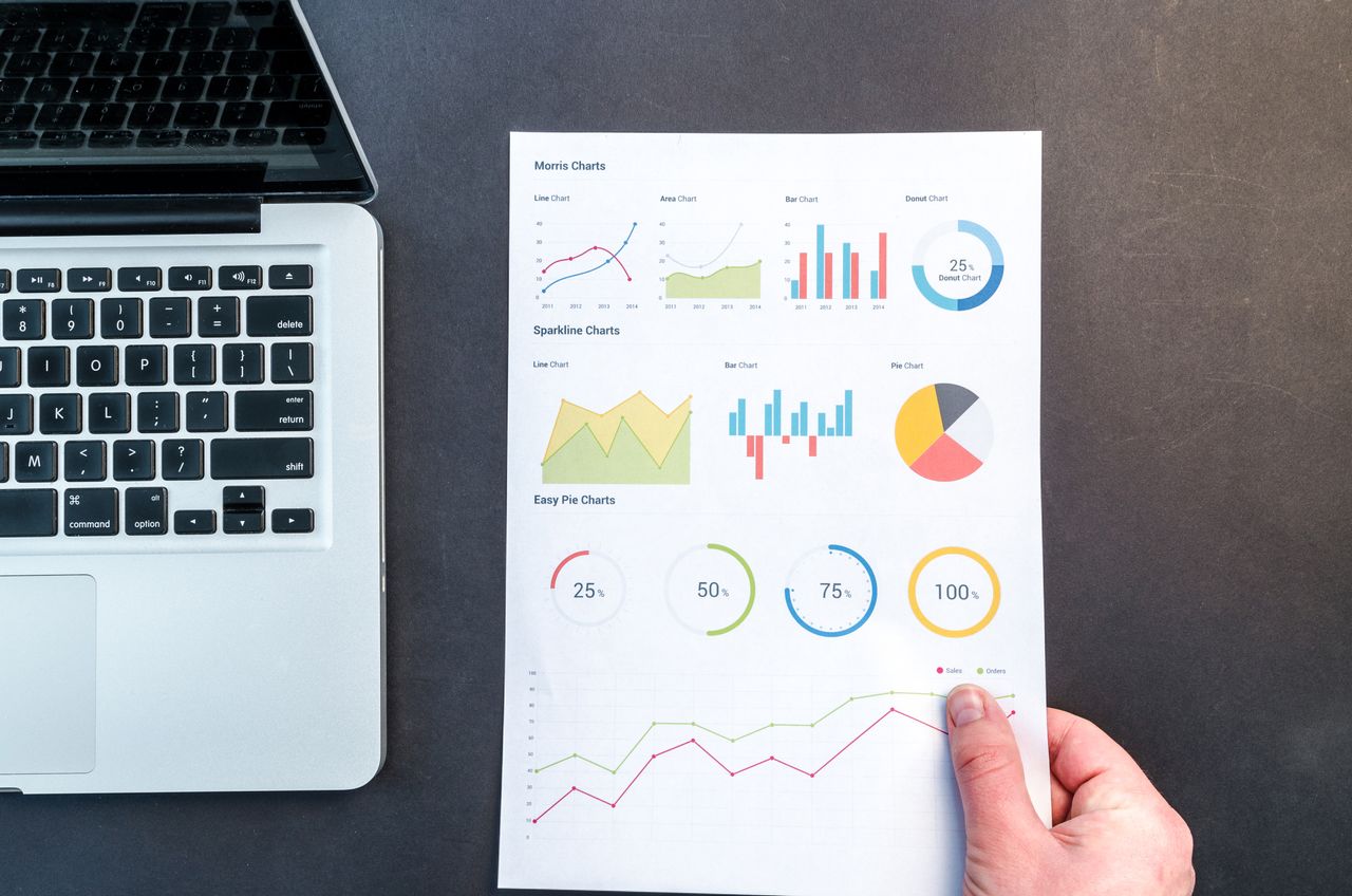 Services Detailed charts and graphs on a document next to a laptop, representing data analysis.